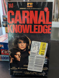 Collector displays a sealed VHS copy of the movie "Carnal Knowledge," priced at $18.96.
