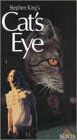 Stephen King's "Cat's Eye" book cover features a large, ominous cat face looming over a woman in a white dress.
