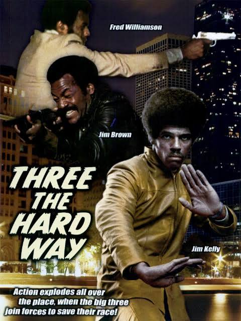 Movie poster for "Three the Hard Way" features Fred Williamson aiming a gun, Jim Brown brandishing a weapon, and Jim Kelly doing a martial arts pose in front of a cityscape.
