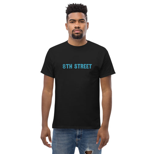 Man models a black 8th Street graphic tee with jeans.

