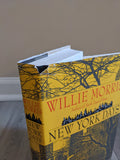 Close-up shows a slightly damaged hardcover of "New York Days" by Willie Morris, with a yellow cover featuring a cityscape and bare trees.
